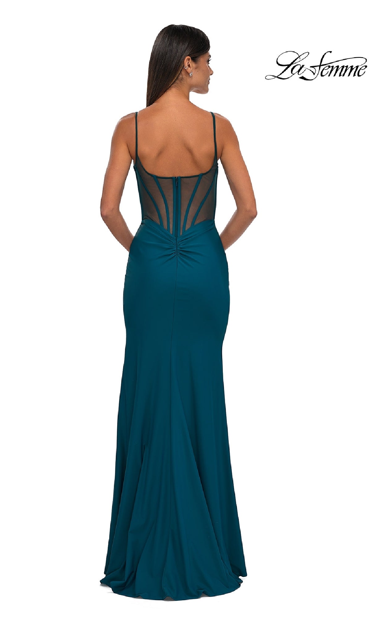 A woman stands with her back to the camera in the teal La Femme 32763 Prom Dress, a fitted, floor-length gown featuring a plunging V-neck, thin straps, and a sheer back panel for an elegant evening look.